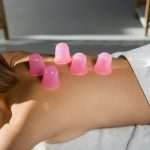 cropped view of young woman with pink massage cups on back receiving vacuum massage