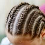 Girl with many small braids. Texture of plaits. Close-up, selective focus