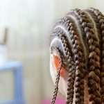 Hairstyle with many small plaited braids. Rear view, close-up. Selective focus.