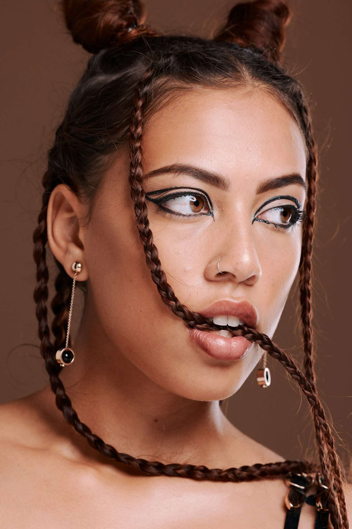 Makeup, hair and woman biting braid with edgy hairstyle and beauty on a brown studio background. Tr