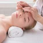 Woman gets eyelashes tinting by beautician at spa